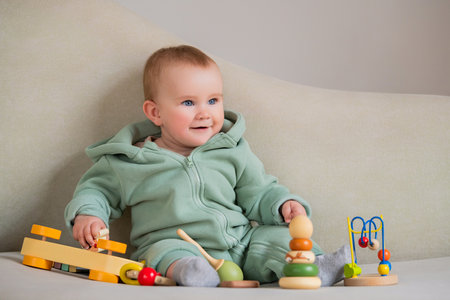 A baby is sitting on a couch with a variety of toys around him. Concept of fun and innocence, as the baby is surrounded by colorful and engaging toys. The image captures a moment of joyの写真素材