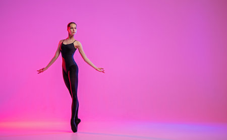 young ballerina in pointe shoes dances in a black leotard and leotard on a red backgroundの写真素材