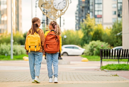 Two happy children walk to school with backpacks along a sunny city street. Concept of back to school, learning, friendship and childhood.の写真素材