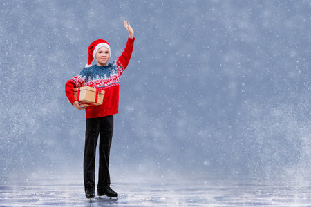 Boy figure skater in Santa Claus hat skating on ice. Winter sports for kids. Christmas card with copy space.の写真素材