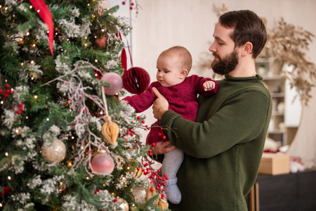 winter holidays and family concept - happy middle-aged father and baby daughter decorating christmas...