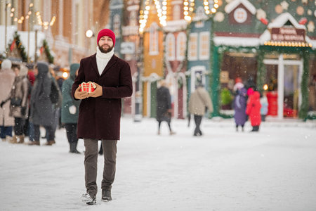 Happy smiling man in winter clothes at street Christmas market walking with gifts in hands. Christmas shopping.の写真素材