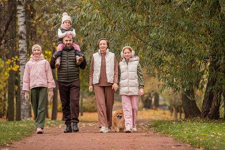 happy traditional family with many children is walking in an autumn park. Mom, dad and three...