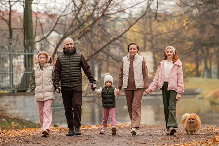 large family with many children walks together hand in hand through an autumn city park. Quiet,...