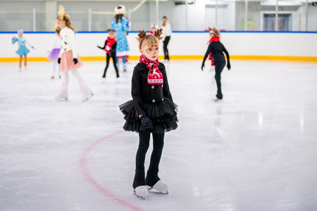 Little girl in reindeer costume skating on ice rink, children's sports festival, Christmas.の写真素材