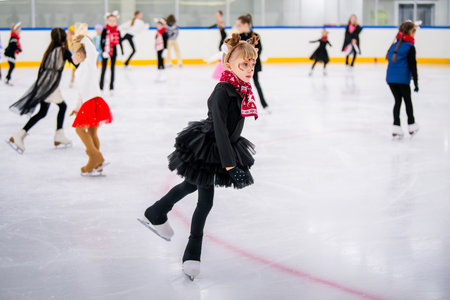 Little girl in reindeer costume skating on ice rink, children's sports festival, Christmas.の写真素材