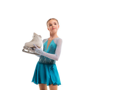 Young figure skater in bright costume holding skates - preparation for ice performance. Portrait of girl isolated on white background.の写真素材