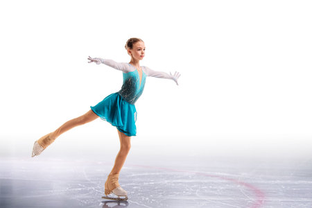 Young figure skater in bright costume posing. Portrait of girl isolated on white background.の写真素材
