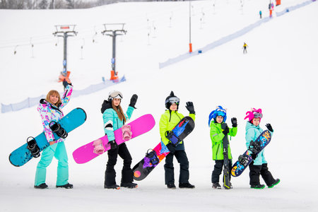 Large family with children enjoying snowboarding on a ski resort slope. Winter sports and outdoor fun.の写真素材