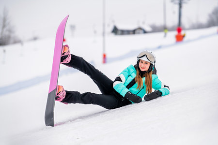 Young female snowboarder on a snowy slope, dressed in stylish winter gear. Exciting winter sports and outdoor adventure.の写真素材