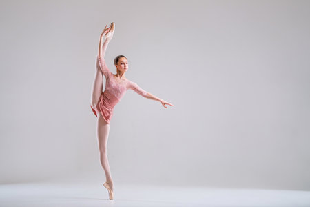 a young slender ballerina in pointe shoes and a pink leotard dances on a white backgroundの写真素材