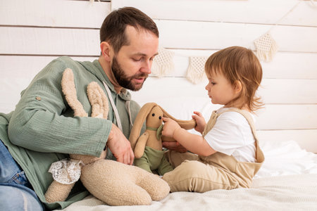 A cheerful baby plays on a cozy bed with a loving father. Harmonious development and educational games in the atmosphere of home.の写真素材