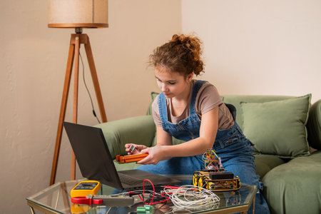young girl working on a robotics project, carefully connecting wires and using a multimeter. The scene represents education, engineering skills, and creativity in technologの写真素材