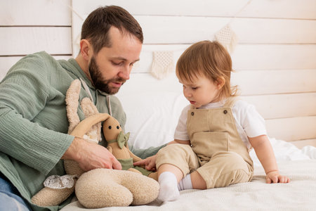 A cheerful baby plays on a cozy bed with a loving father. Harmonious development and educational games in the atmosphere of home.の写真素材