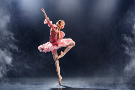 little ballerina gracefully performs a ballet pose, demonstrating elegance and skill in a classic pink tutu on pointe shoes.の写真素材