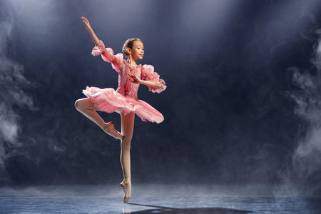 little ballerina gracefully performs a ballet pose, demonstrating elegance and skill in a classic pink tutu on pointe shoes.の写真素材
