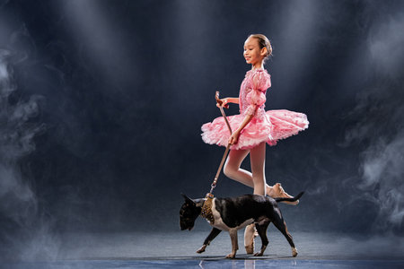 young ballerina dances in a pink tutu next to a dog. The contrast between the ballerina's sophistication and the dog's squatness.の写真素材
