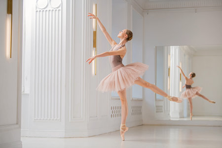 ballerina performs a graceful dance in a rehearsal studio, demonstrating posture and elegance. The dancer wears a flowing tutu and pointe shoes.の写真素材
