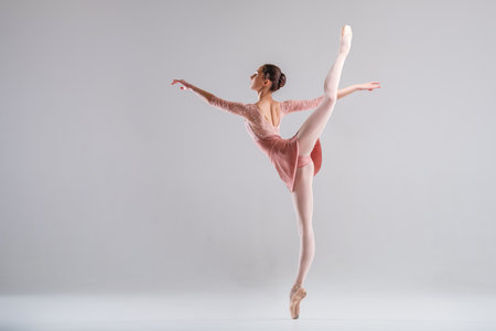 a young slender ballerina in pointe shoes and a pink leotard dances on a white backgroundの写真素材