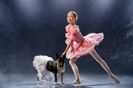 young ballerina dances in a pink tutu next to a bull terrier.の写真素材