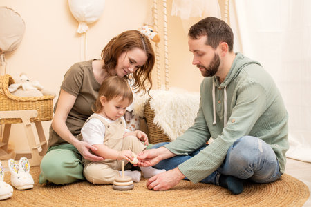 loving young family enjoys quality time together in a beautifully decorated nursery. The parents engage their toddler in an educational game, creating a warm and joyful atmosphereの写真素材