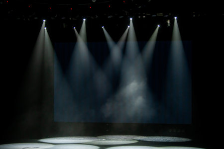 Empty stage lit by multiple spotlights, creating a dramatic and atmospheric scene. The beams of...