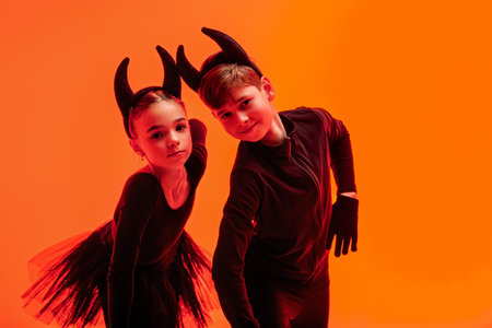 Children in devil costumes. Graceful young figure skaters in Halloween-themed costumesの写真素材