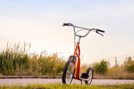 Kick scooter standing on the edge of an asphalt road. Off-road transport for sport and activity. Travel and outdoor recreation concept.の写真素材