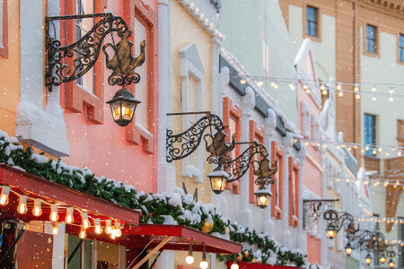 Cozy winter street view with building facades, snow, and illuminated lanterns, evoking a festive Christmas market scene for holiday design.の写真素材