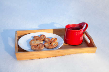 Red mug with cookies on the snow.の写真素材