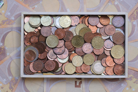 Coins in a wooden box on the background of banknotes.