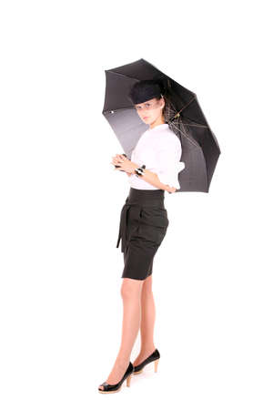A young beautiful lady with a watch on her hand in a blak hat holding an umbrella standing over white backgroundの写真素材