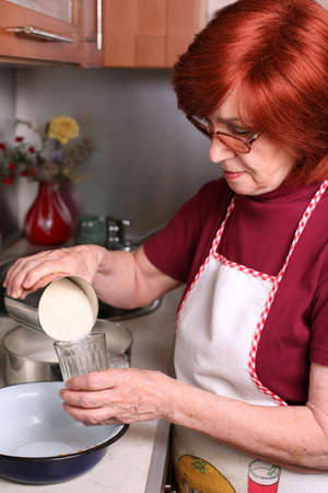 A grandmother is pouring sugar to the glassの写真素材
