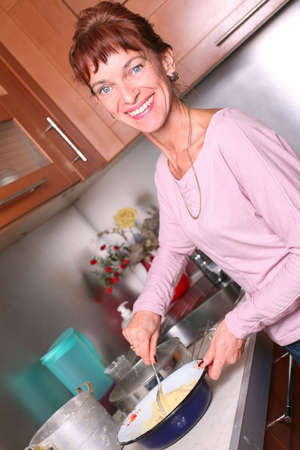 Smiling woman  kneads dough in the kitchenの写真素材