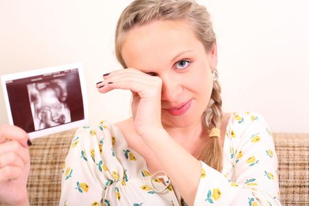 Happy pregnant woman is holding  a sonogram of her unborn child 