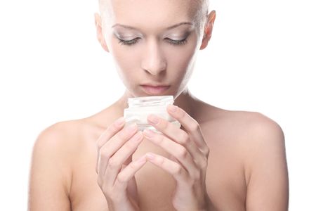 Beautiful woman is holding a cream in her hand over white backgroundの写真素材