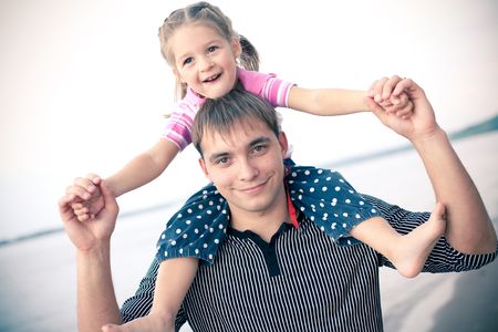 Outdoor portrait of young father with a daughter on his shouldersの写真素材