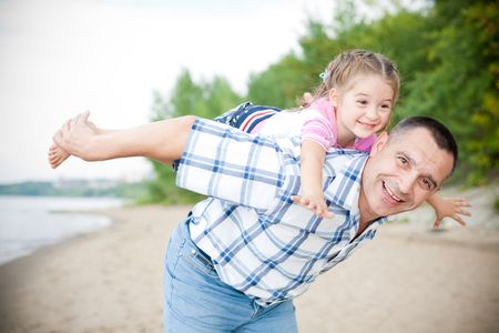 Middle-aged caucasian man playing with a little girl on the beachの写真素材