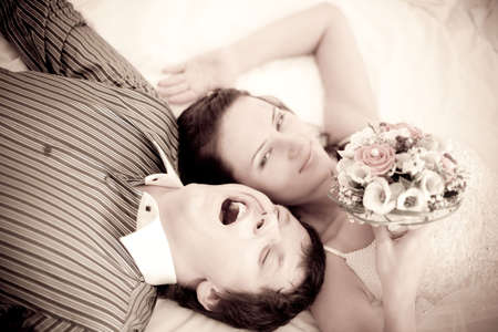 Portrait of a tired bride and gape groom which are lying on the bedの写真素材