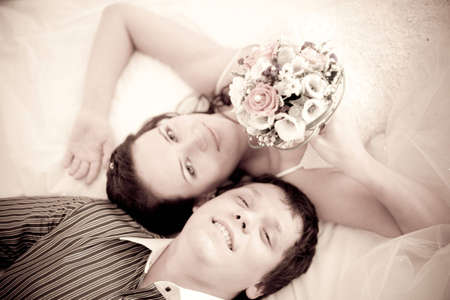 Portrait of an attractive bride and a groom which are lying on the bedの写真素材