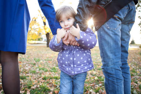 Sad little girl holds parent's handsの写真素材