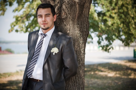 Handsome groom is standing near the treeの写真素材