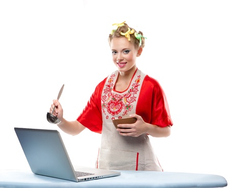 Woman is cooking with the recipe on a laptop over white backgroundの写真素材