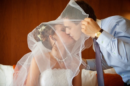 Newlywed couple kissing each other in the bedroomの写真素材