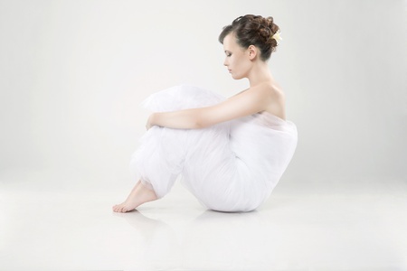 Attractive young woman wrapped in fabric sitting on the floorの写真素材