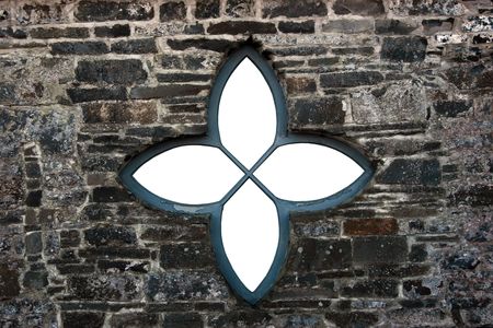 an old castle star shaped window against a stone wallの写真素材