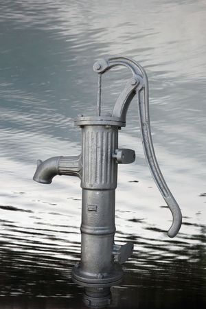 an old water pump against a water backgroundの写真素材