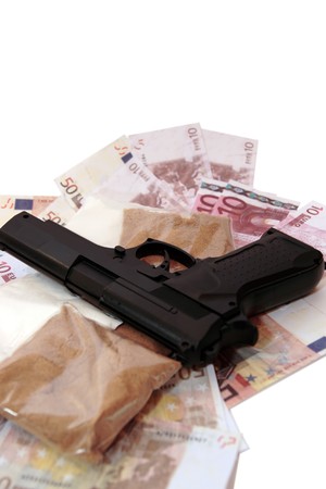 a stash of drugs gun and money showing a dangerous cost to life against a white backgroundの写真素材