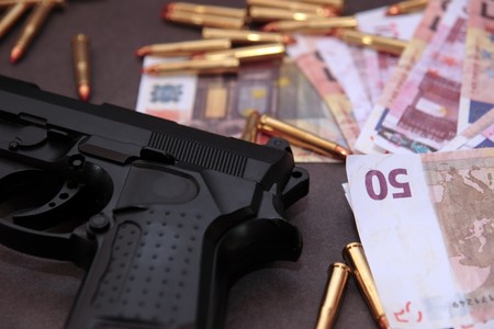 a stash of drugs gun and money showing a dangerous cost to life against a dark backgroundの写真素材