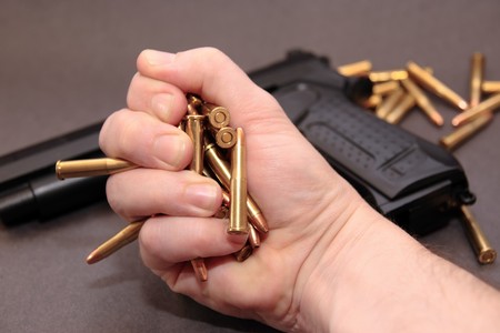 a stash of bullets in the hands and a gunの写真素材